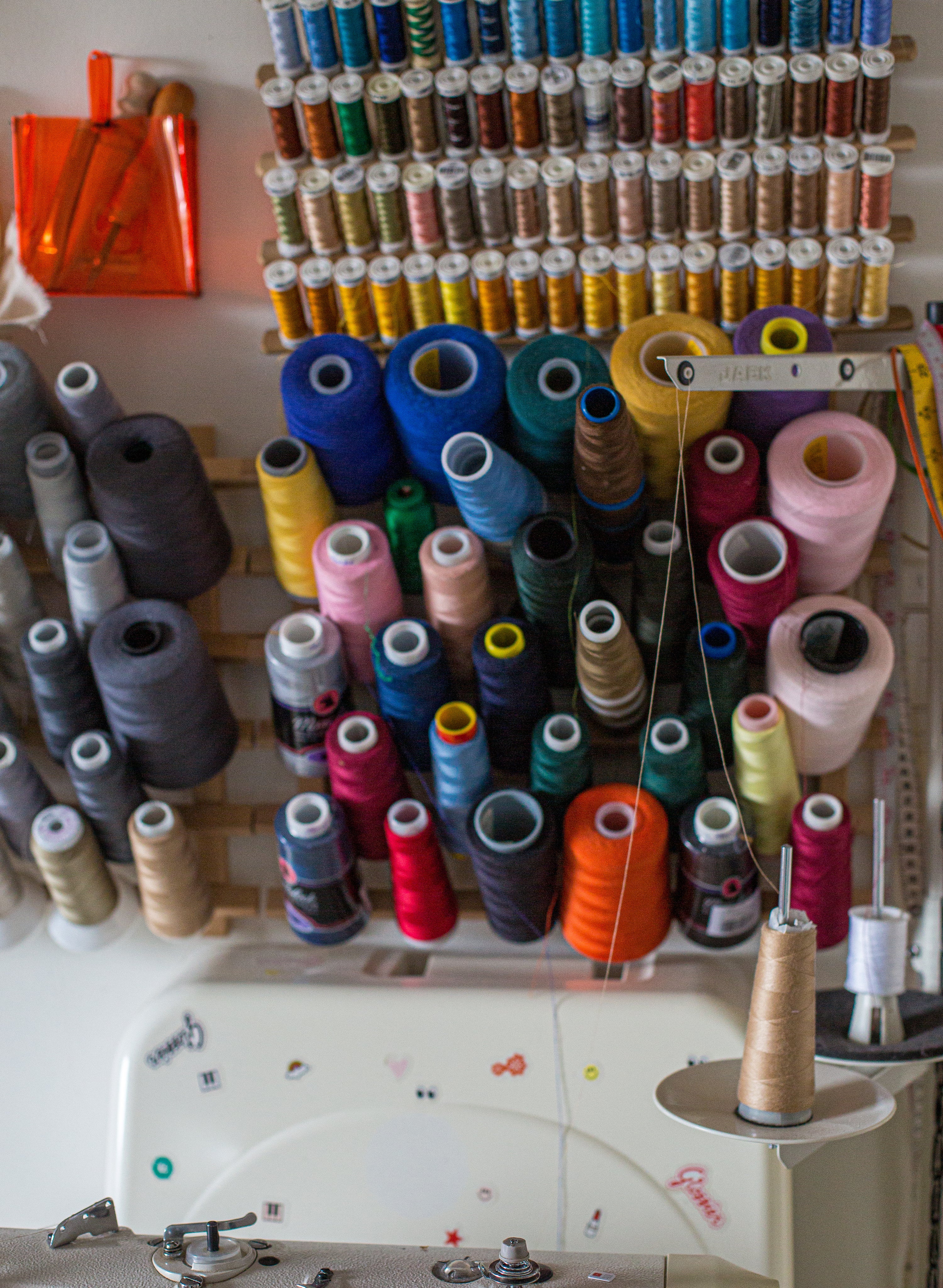 a-wall-with-spools-of-thread-on-a-wooden-rack.jpg
